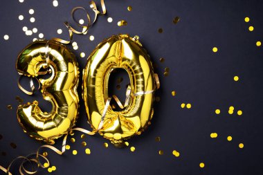 Altın folyo balon numarası, sayı 30. Doğum günü tebrik kartında 30 yazılıydı. Yıldönümü kutlaması. Pankart. Altın rakamlı, siyah arkaplan. Sayısal rakam, ışık bokeh, parıltı