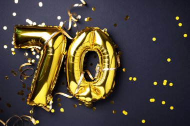 Altın folyo balon numarası, 70. 70 yazısıyla birlikte doğum günü tebrik kartı. Yıldönümü kutlaması. Pankart. Altın rakamlı, siyah arkaplan. Sayısal rakam, ışık bokeh, parıltı