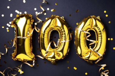 Altın folyo balon numarası, 100 haneli rakam. Doğum günü tebrik kartında 100 yazılıydı. Yıldönümü kutlaması. Pankart. Altın rakamlı, siyah arkaplan. Sayısal rakam, ışık bokeh, parıltı.
