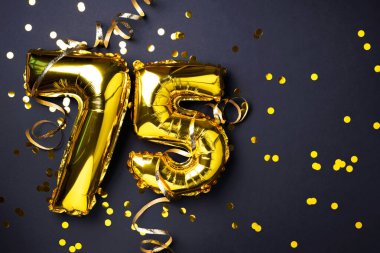 Altın folyo balon numarası, rakam 75. Doğum günü tebrik kartında 75 yazılıydı. Yıldönümü kutlaması. Pankart. Altın rakamlı, siyah arkaplan. Sayısal rakam, ışık bokeh, parıltı.