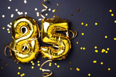 Altın folyo balon numarası, seksen beş. 85 yazısıyla birlikte doğum günü tebrik kartı. Yıldönümü kutlaması. Pankart. Altın rakamlı, siyah arkaplan. Sayısal rakam, ışık bokeh, parıltı.