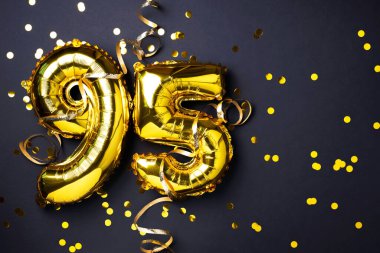 Altın folyo balon numarası, doksan beş. Doğum günü tebrik kartında 95 yazılıydı. Yıldönümü kutlaması. Pankart. Altın rakamlı, siyah arkaplan. Sayısal rakam, ışık bokeh, parıltı.