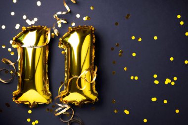 Altın folyo balon numarası, on bir numara. Doğum günü tebrik kartı, 11. yazı. Yıldönümü kutlaması. Pankart. Şık altın rakamlı, açık renkli, parlak, siyah arkaplan. Sayısal rakam.
