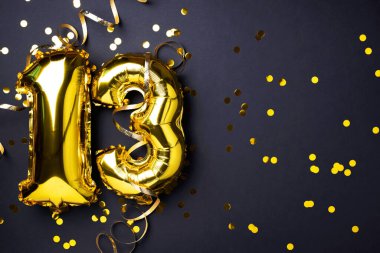 Altın folyo balon numarası, 13 numara. Doğum günü tebrik kartı, 13. yazı. Yıldönümü kutlaması. Pankart. Şık altın rakamlı, açık renkli, parlak, siyah arkaplan. Sayısal rakam.