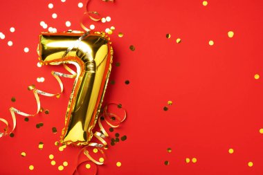 Altın folyo balon numarası ve 7 haneli rakam. Doğum günü tebrik kartı. Yıldönümü kutlaması. Pankart. Uzayı kopyala Şık altın rakamlı, parlak parıltılı, kırmızı arkaplan. Sayısal rakam
