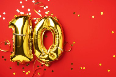 Altın folyo balon numarası, on numara. Doğum günü tebrik kartında 10 yazılıydı. Yıldönümü kutlaması. Pankart. Altın rakamlı, kırmızı arkaplan. Sayısal rakam, parlak parlak parıltı.