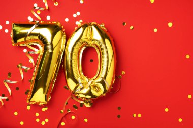 Altın folyo balon numarası, 70. 70 yazısıyla birlikte doğum günü tebrik kartı. Yıldönümü kutlaması. Pankart. Altın rakamlı, kırmızı arkaplan. Sayısal rakam, parlak parlak parıltı