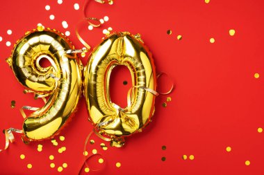 Altın folyo balon numarası, doksan haneli. Doğum günü tebrik kartı ve 90 numaralı yazı. Yıldönümü kutlaması. Pankart. Altın rakamlı, kırmızı arkaplan. Sayısal rakam, parlak parlak parıltı