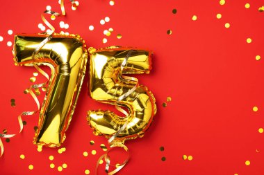Altın folyo balon numarası, rakam 75. Doğum günü tebrik kartında 75 yazılıydı. Yıldönümü kutlaması. Pankart. Altın rakamlı, kırmızı arkaplan. Sayısal rakam, parlak parlak parıltı.
