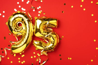 Altın folyo balon numarası, doksan beş. Doğum günü tebrik kartında 95 yazılıydı. Yıldönümü kutlaması. Pankart. Altın rakamlı, kırmızı arkaplan. Sayısal rakam, parlak parlak parıltı.