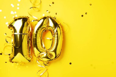 Altın folyo balon numarası, on numara. Doğum günü tebrik kartı, 10. yazı. Yıldönümü kutlaması. Pankart. Altın rakamlı, sarı arkaplan. Sayısal rakam, parlak parlak parıltı.