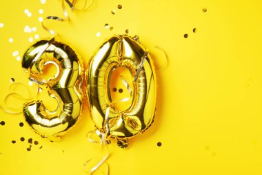 Altın folyo balon numarası, sayı 30. Doğum günü tebrik kartında 30 yazılıydı. Yıldönümü kutlaması. Pankart. Altın rakamlı, sarı arkaplan. Sayısal rakam, parlak parlak parıltı