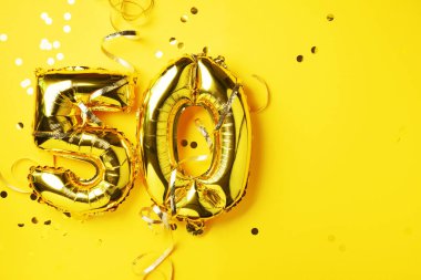 Altın folyo balon numarası, 50 haneli. Doğum günü tebrik kartı, yazıt 50. Yıldönümü kutlaması. Pankart. Altın rakamlı, sarı arkaplan. Sayısal rakam, parlak parlak parıltı
