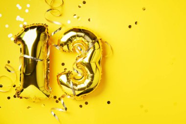 Altın folyo balon numarası, 13 numara. Doğum günü tebrik kartı, 13. yazı. Yıldönümü kutlaması. Pankart. Şık altın rakamlı, parlak parıltılı, sarı arkaplan. Sayısal rakam.