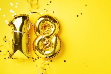 Altın folyo balon numarası, sayı 18. Doğum günü tebrik kartı, 18. yazı. Yıldönümü kutlaması. Pankart. Şık altın rakamlı, parlak parıltılı, sarı arkaplan. Sayısal rakam.