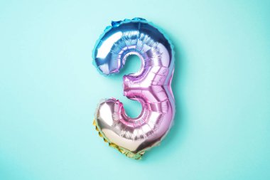 Yaratıcı düzen. Gökkuşağı folyo balon numarası ve rakam üç üç. Doğum günü tebrik kartı. Yıldönümü konsepti. Üst Manzara. Uzayı kopyala Mavi arkaplan üzerinde renkli sayılar. Sayısal rakam