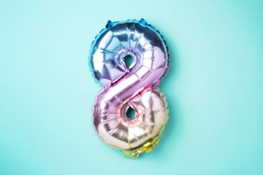 8 Mart. Mutlu Kadınlar Günü. Yaratıcı düzen. Gökkuşağı folyo balon numarası ve rakam sekiz sekiz. Doğum günü tebrik kartı. Yıldönümü konsepti. Üst Manzara. Mavi arkaplan üzerinde renkli sayı. Sayısal rakam