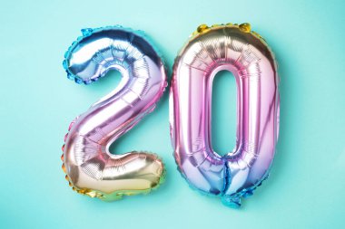Gökkuşağı folyo balon numarası, sayı 20. Üzerinde 20 yazan doğum günü tebrik kartı. Yıldönümü konsepti. Üst Manzara. Mavi arka planda renkli sayı. Sayısal rakam, kutlama olayı, şablon.