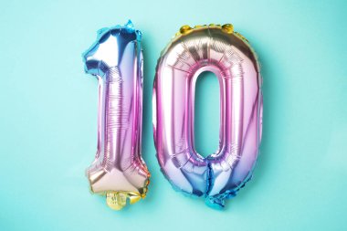 Gökkuşağı folyo balon numarası, on numara. Doğum günü tebrik kartında 10 yazılıydı. Yıldönümü konsepti. Üst Manzara. Mavi arka planda renkli sayı. Sayısal rakam, kutlama olayı, şablon.