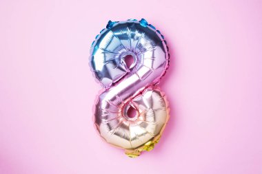 8 Mart. Mutlu Kadınlar Günü. Yaratıcı düzen. Gökkuşağı folyo balon numarası ve rakam sekiz sekiz. Doğum günü tebrik kartı. Yıldönümü konsepti. Üst Manzara. Pembe arka planda renkli sayılar var. Sayısal rakam