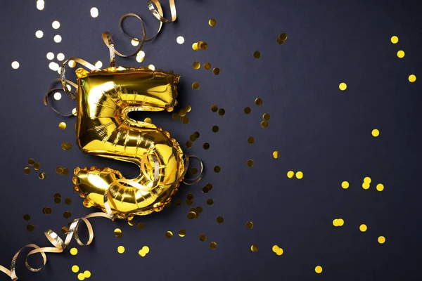 Altın folyo balon numarası ve rakam 5-5. Doğum günü tebrik kartı. Yıldönümü kutlaması. Pankart. Uzayı kopyala Şık altın rakamlı, açık renkli, parlak, siyah arkaplan. Sayısal rakam