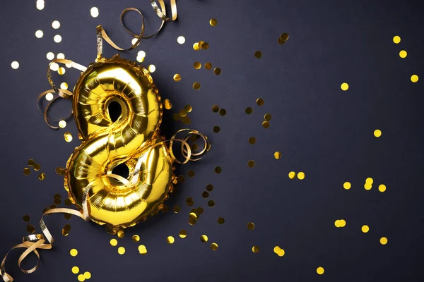 8 Mart. Mutlu Kadınlar Günü. Altın folyo balon numarası ve rakam sekiz sekiz. Doğum günü tebrik kartı. Yıldönümü kutlaması. Pankart. Altın rakamlı, siyah arkaplan. Sayısal rakam