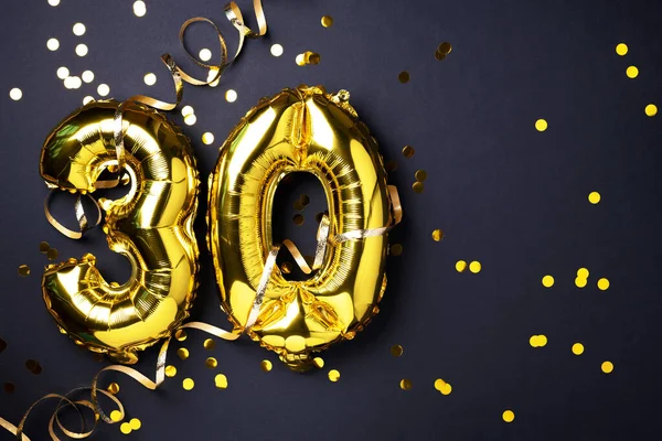 Altın folyo balon numarası, sayı 30. Doğum günü tebrik kartında 30 yazılıydı. Yıldönümü kutlaması. Pankart. Altın rakamlı, siyah arkaplan. Sayısal rakam, ışık bokeh, parıltı