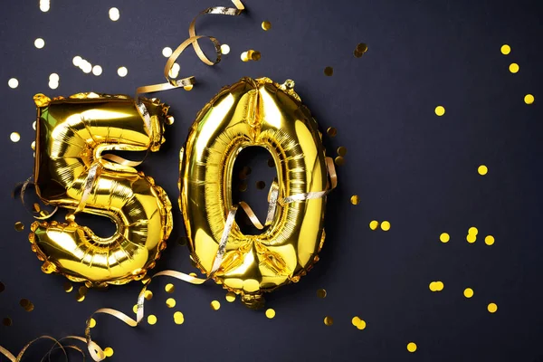 Altın folyo balon numarası, 50 haneli. Doğum günü tebrik kartında 50 yazılıydı. Yıldönümü kutlaması. Pankart. Altın rakamlı, siyah arkaplan. Sayısal rakam, ışık bokeh, parıltı