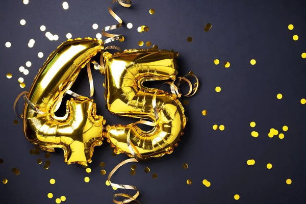 Altın folyo balon numarası, 45 haneli rakam. 45 yazılı doğum günü tebrik kartı var. Yıldönümü kutlaması. Pankart. Altın rakamlı, siyah arkaplan. Sayısal rakam, ışık bokeh, parıltı.