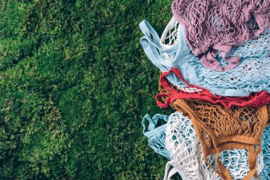 Renkli yeniden kullanılabilir ağ torbaları ya da yeşil çimlerde ağ alışverişçileri, yosun arka planı. Sıfır atık, plastiksiz konsept. Üst Manzara. Çevre dostu ağ tüccarı. Sürdürülebilir, ekoloji, organik yaşam tarzı.