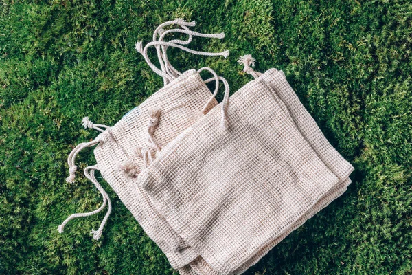 Reusable eco friendly canvas bag on green grass, moss background. Top view. Copy space. Zero waste, plastic free concept. Eco friendly shopper. Sustainable, organic, ecology lifestyle.