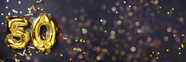 Altın folyo balon numarası, 50 haneli. Doğum günü tebrik kartında 50 yazılıydı. Yıldönümü kutlaması. Pankart. Altın rakamlı, siyah arkaplan. Sayısal rakam, ışık bokeh, parıltı