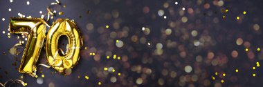 Altın folyo balon numarası, 70. 70 yazısıyla birlikte doğum günü tebrik kartı. Yıldönümü kutlaması. Pankart. Altın rakamlı, siyah arkaplan. Sayısal rakam, ışık bokeh, parıltı