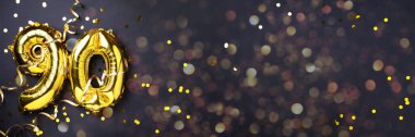 Altın folyo balon numarası, doksan haneli. Doğum günü tebrik kartı ve 90 numaralı yazı. Yıldönümü kutlaması. Pankart. Altın rakamlı, siyah arkaplan. Sayısal rakam, ışık bokeh, parıltı