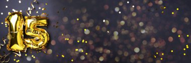 Altın folyo balon numarası, rakam 15. Doğum günü tebrik kartı, 15. yazı. Yıldönümü kutlaması. Pankart. Şık altın rakamlı, açık renkli, parlak, siyah arkaplan. Sayısal rakam.