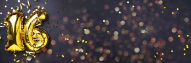 Altın folyo balon numarası, sayı 16. Doğum günü tebrik kartı, 16. yazı. Yıldönümü kutlaması. Pankart. Şık altın rakamlı, açık renkli, parlak, siyah arkaplan. Sayısal rakam.