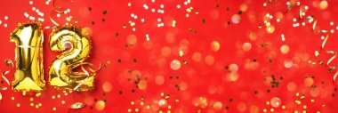 Altın folyo balon numarası, on iki numara. Doğum günü tebrik kartı, 12. yazı. Yıldönümü kutlaması. Pankart. Şık altın rakamlı, parlak, kırmızı arkaplan. Sayısal rakam.