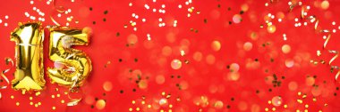 Altın folyo balon numarası, rakam 15. Doğum günü tebrik kartı, 15. yazı. Yıldönümü kutlaması. Pankart. Şık altın rakamlı, parlak, kırmızı arkaplan. Sayısal rakam.
