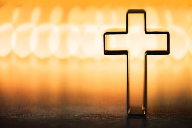 Christian cross on yellow background with soft bokeh lights background. Copy space. Banner. Church worship, salvation concept. Faith symbol in Jesus Christ. Holy cross for good friday, Easter day.