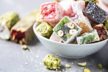 Traditional turkish delight on grey background. Arab dessert, baklava, halva, rahat lokum, sherbet, nuts, pistachios in bowl on grey background.
