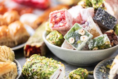 Traditional turkish delight on grey background. Arab dessert, baklava, halva, rahat lokum, sherbet, nuts, pistachios in bowl on grey background.