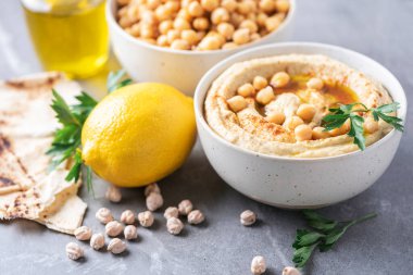 Hummus, chickpea dip, olive oil, raw beans, smoked paprika, pita on grey authentic background. Middle eastern, jewish cuisine or arabic dishes. Macro view. Copy space. Vegan, vegetarian food concept.