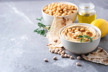 Chickpeas hummus, olive oil, raw chickpeas, smoked paprika, pita on grey background. Middle eastern, jewish cuisine or arabic dishes. Macro view. Copy space. Snacks set. Vegan, vegetarian food concept.