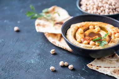 Humus, nohut sosu, zeytinyağı, çiğ fasulye, tütsülenmiş paprika, koyu otantik arka planda pide. Ortadoğu, Yahudi mutfağı ya da Arap yemekleri. Üst Manzara. Uzayı kopyala Vejetaryen, vejetaryen gıda konsepti.