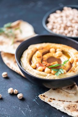Humus, nohut sosu, zeytinyağı, çiğ fasulye, tütsülenmiş paprika, koyu otantik arka planda pide. Ortadoğu, Yahudi mutfağı ya da Arap yemekleri. Üst Manzara. Uzayı kopyala Vejetaryen, vejetaryen gıda konsepti.