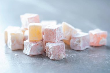 Turkish delight - rahat lokum or lokum with sugar powder on grey background. Traditional eastern cuisine. Traditional middle eastern sweets. Jewish, turkish, arabic national dessert. Turkish delight.