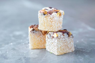 Turkish delight - lokum or rahat lokum with pistachios on grey background. Traditional eastern cuisine. Traditional middle eastern sweets. Jewish, turkish, arabic national dessert. Turkish delight.