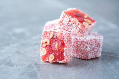 Turkish delight - lokum or rahat lokum with hazelnuts on grey background. Traditional eastern cuisine. Traditional middle eastern sweets. Jewish, turkish, arabic national dessert. Turkish delight.