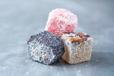 Turkish delight with poppy on grey background. Copy space. Traditional eastern cuisine. Traditional middle eastern sweets. Jewish, turkish, arabic national dessert. Turkish delight.
