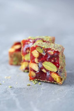 Turkish delight - lokum or rahat lokum with pistachios on grey background. Traditional eastern cuisine. Traditional middle eastern sweets. Jewish, turkish, arabic national dessert. Turkish delight.